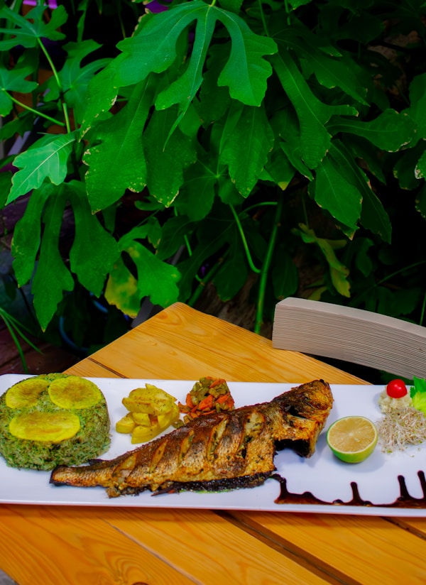 delectable fish dish served on a plate, perfectly paired with the lush green backdrop of a serene restaurant setting